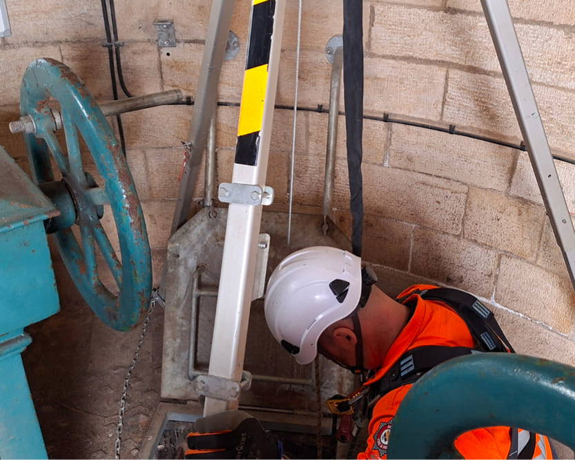 A technical rescue operative wearing high-visibility overalls evaluating a Confined Space Rescue operation