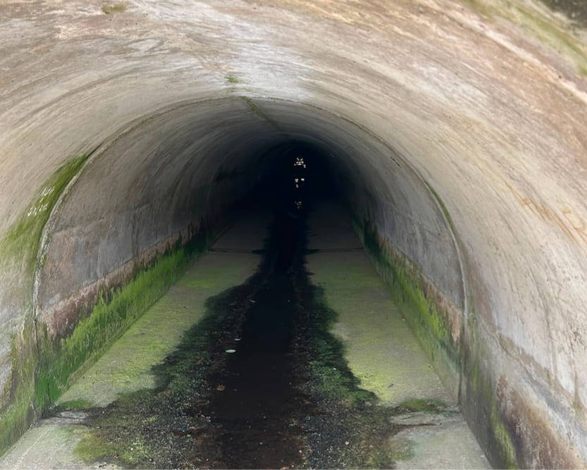 A long dark tunnel with a person in high-visibility seen in the darkness, working for AGO Fire & Rescue as part of a Confined Space Rescue