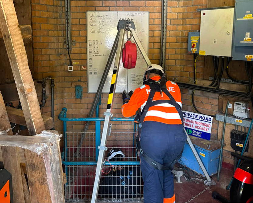 A person in high-vis workwear assisting another person in entering a Confined Space as part of a rescue