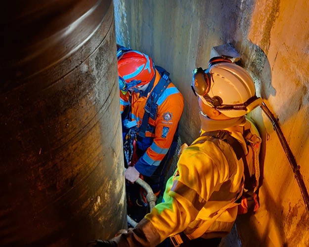 Two people in high-vis workwear assisting with a Confined Space Rescue