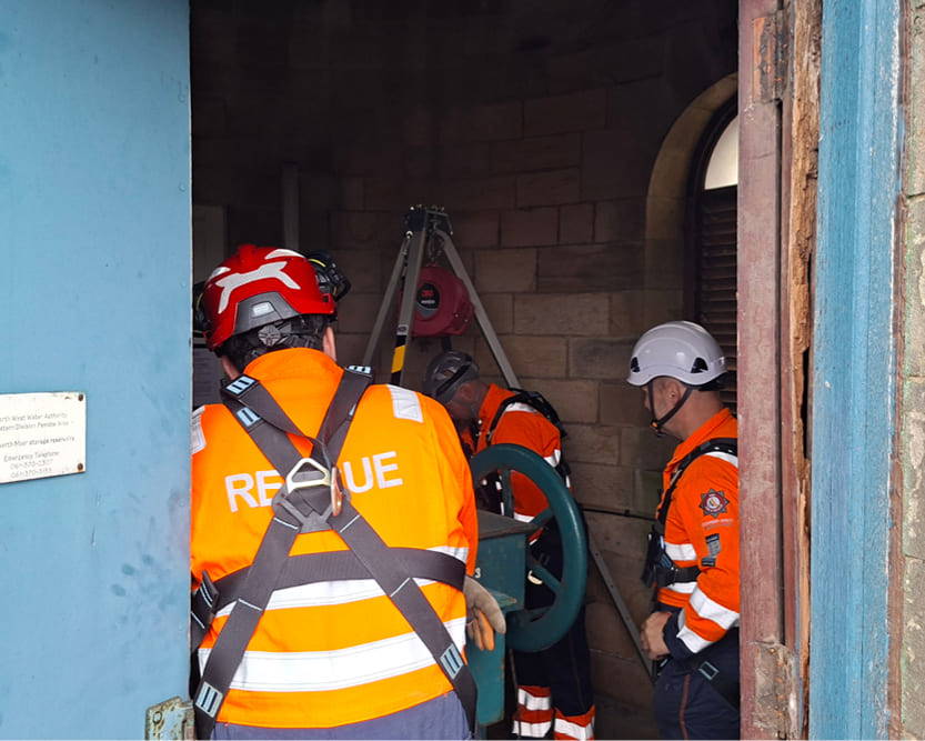 A team of technical rescue operative all wearing high-visibility overalls assisting with a Confined Space Rescue operation